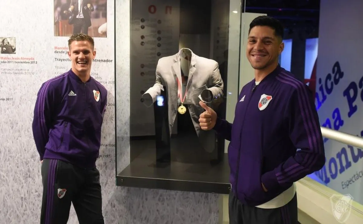 Zuculini y Enzo Pérez posando frente al saco de Gallardo, en una visita al Museo.