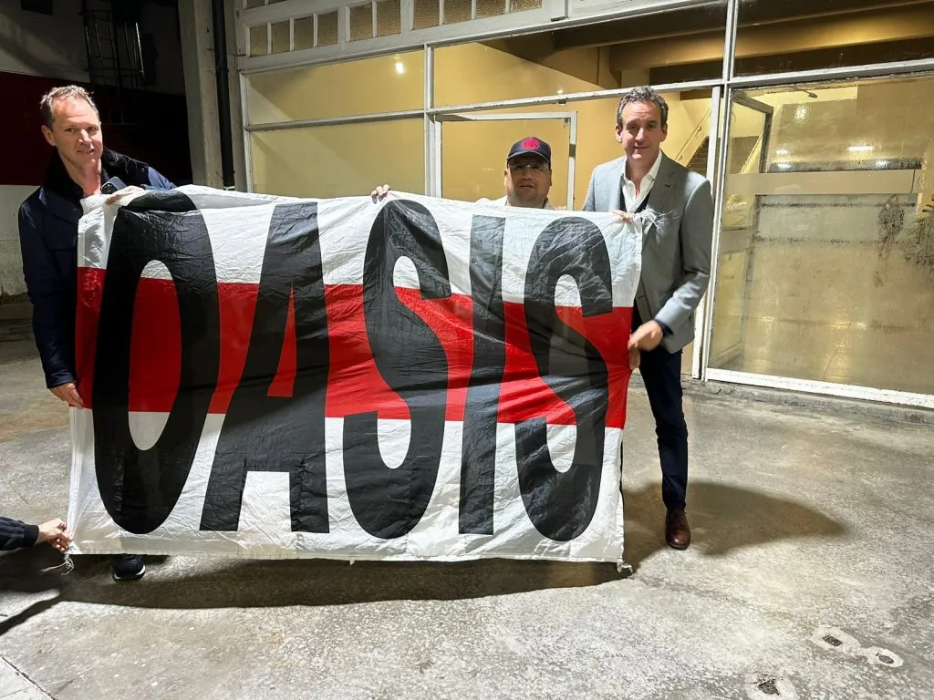 Jorge Brito e Ignacio Villarroel, presidente y vice segundo de River, sostiene junto a Cristian Martínez la famosa bandera de “Oasis”.