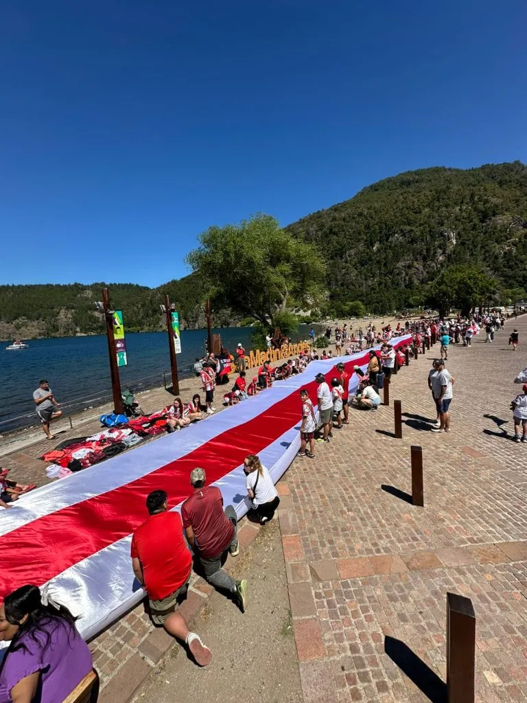 La bandera de River más larga de la Patagonia es una creación de Carmen Castillo, costurera de San Martín de los Andes. En la imagen, desplegada a orillas del lago Lacar.
